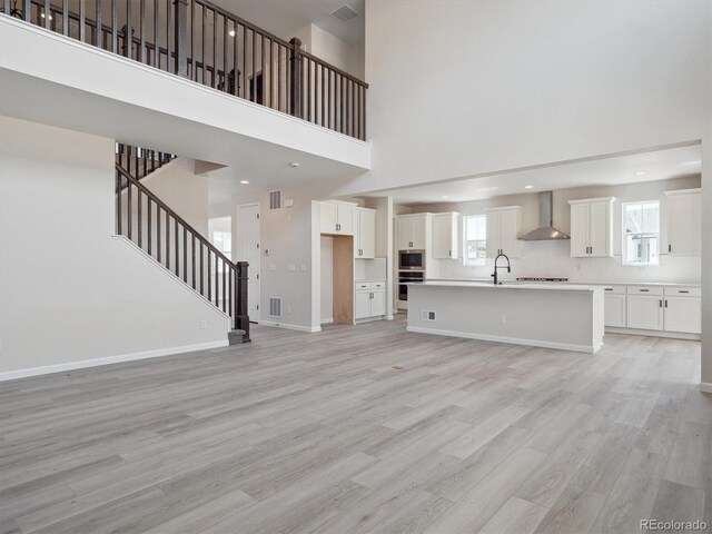 4741 Twelve Oaks Way, Castle Rock, CO 80104 - unfurnished living room featuring a high ceiling, light wood-style floors, stairway, baseboards, and a sink