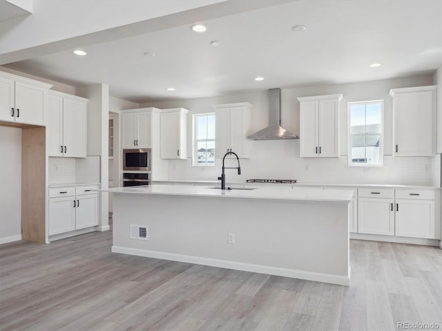4741 Twelve Oaks Way, Castle Rock, CO 80104 - kitchen featuring wall chimney range hood, appliances with stainless steel finishes, a sink, decorative backsplash, and a kitchen island with sink