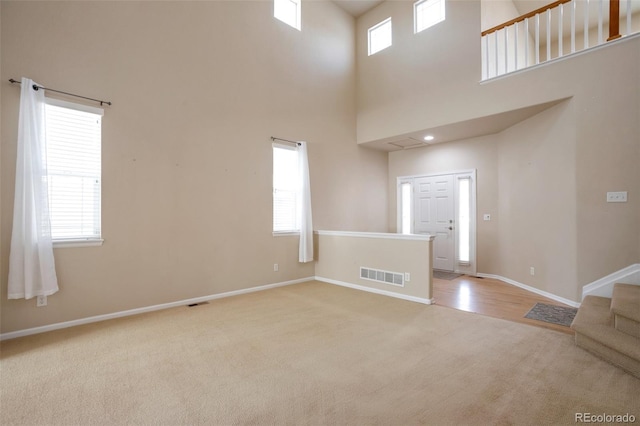 interior space with stairway, a healthy amount of sunlight, visible vents, and baseboards