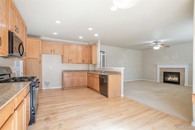 kitchen with light wood-type flooring, black appliances, a sink, a peninsula, and ceiling fan