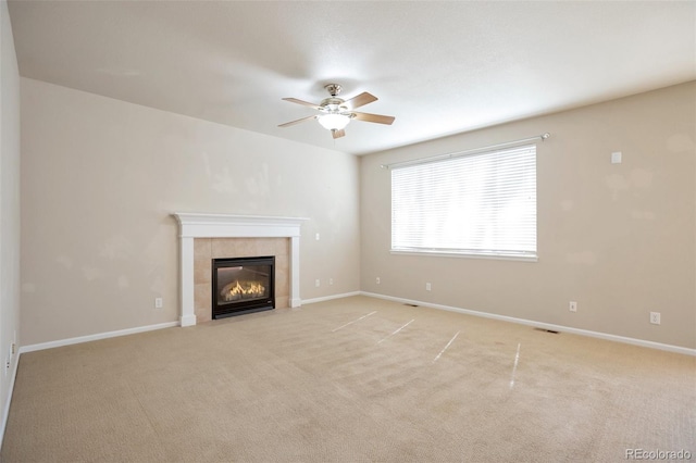 unfurnished living room featuring light carpet, a ceiling fan, baseboards, and a tile fireplace