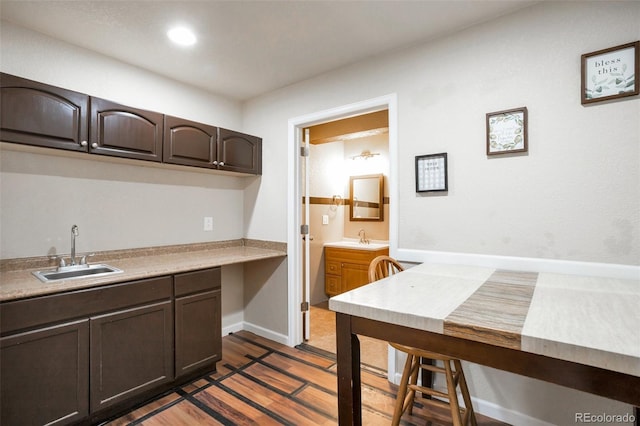 kitchen with a sink, dark brown cabinetry, dark wood finished floors, and light countertops