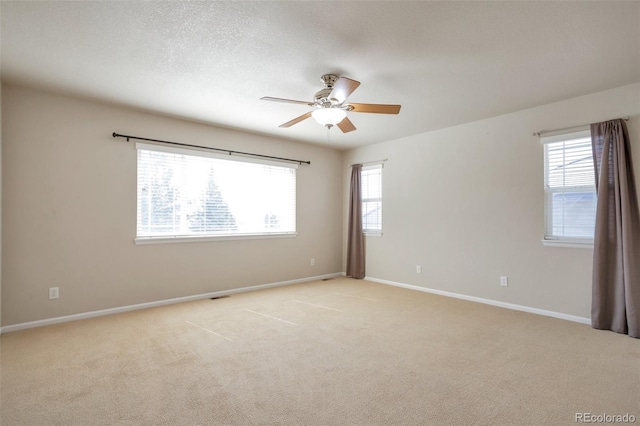 empty room featuring a ceiling fan, baseboards, a wealth of natural light, and light carpet