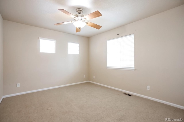 unfurnished room with visible vents, light colored carpet, baseboards, and ceiling fan