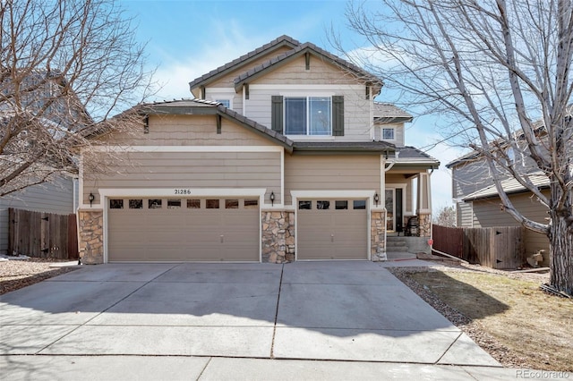 craftsman inspired home featuring stone siding, concrete driveway, and fence