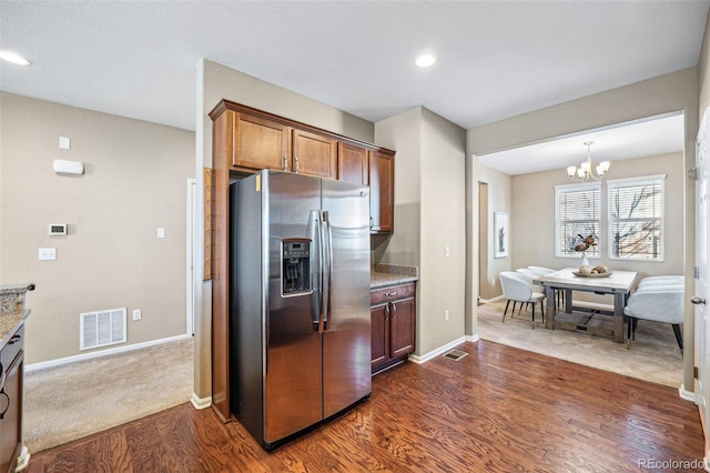 kitchen featuring light stone countertops, an inviting chandelier, dark hardwood / wood-style flooring, and stainless steel fridge with ice dispenser