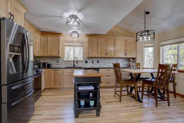 10438 Sunlight Ln, Conifer, CO 80433 - kitchen with stainless steel fridge, light brown cabinetry, plenty of natural light, decorative backsplash, and vaulted ceiling