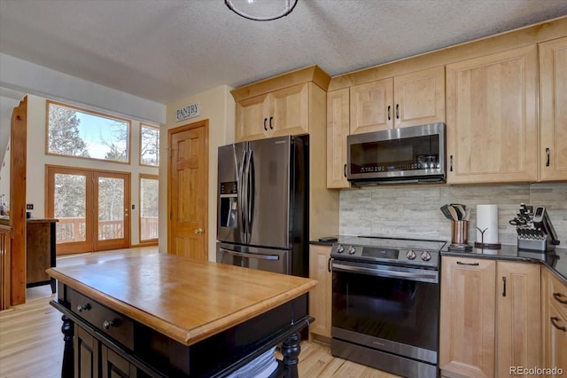10438 Sunlight Ln, Conifer, CO 80433 - kitchen with stainless steel appliances, light brown cabinets, decorative backsplash, light wood-style flooring, and a textured ceiling