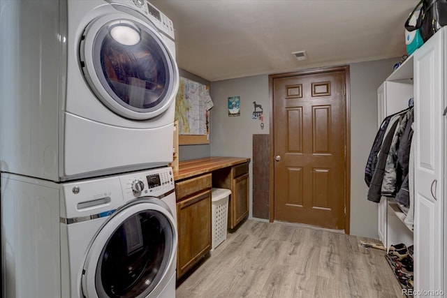 10438 Sunlight Ln, Conifer, CO 80433 - laundry area featuring estacked washer and dryer, cabinet space, and light wood-style flooring