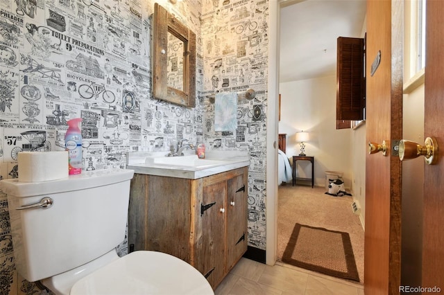 bathroom featuring toilet, vanity, and wallpapered walls