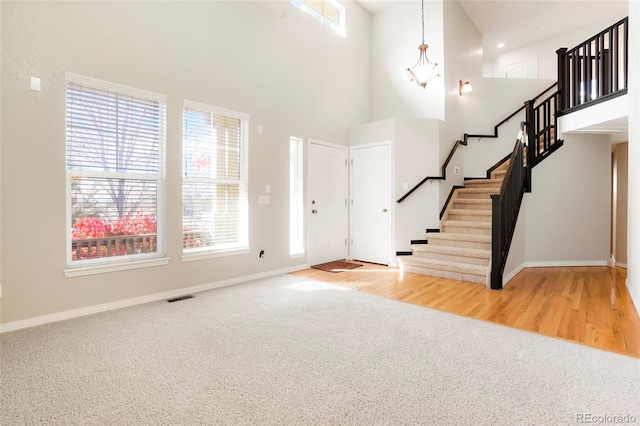 entrance foyer with a towering ceiling and light hardwood / wood-style flooring