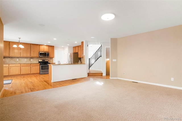 kitchen with decorative backsplash, light hardwood / wood-style flooring, decorative light fixtures, and appliances with stainless steel finishes