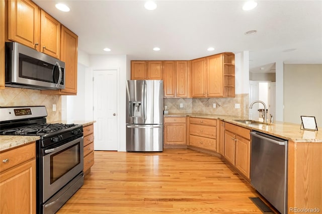 kitchen featuring kitchen peninsula, appliances with stainless steel finishes, light wood-type flooring, and light stone countertops