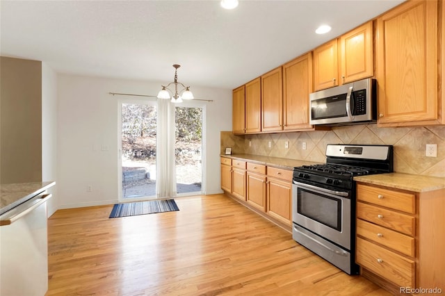 kitchen featuring a chandelier, stainless steel appliances, decorative light fixtures, and light hardwood / wood-style floors