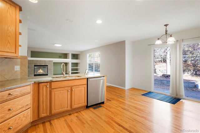 kitchen with stainless steel dishwasher, light hardwood / wood-style floors, sink, and hanging light fixtures