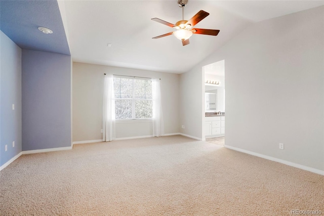 carpeted spare room with ceiling fan and vaulted ceiling