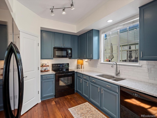 kitchen featuring black appliances, a sink, dark wood-type flooring, light stone counters, and blue cabinets