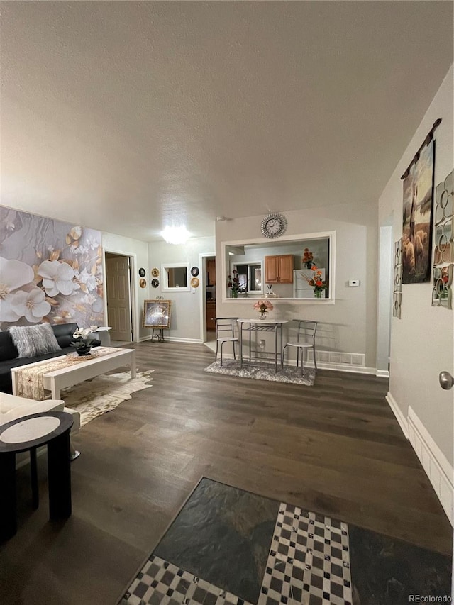 living room with a textured ceiling and dark hardwood / wood-style flooring