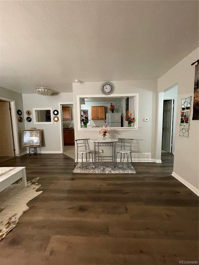 dining space with a textured ceiling and dark wood-type flooring