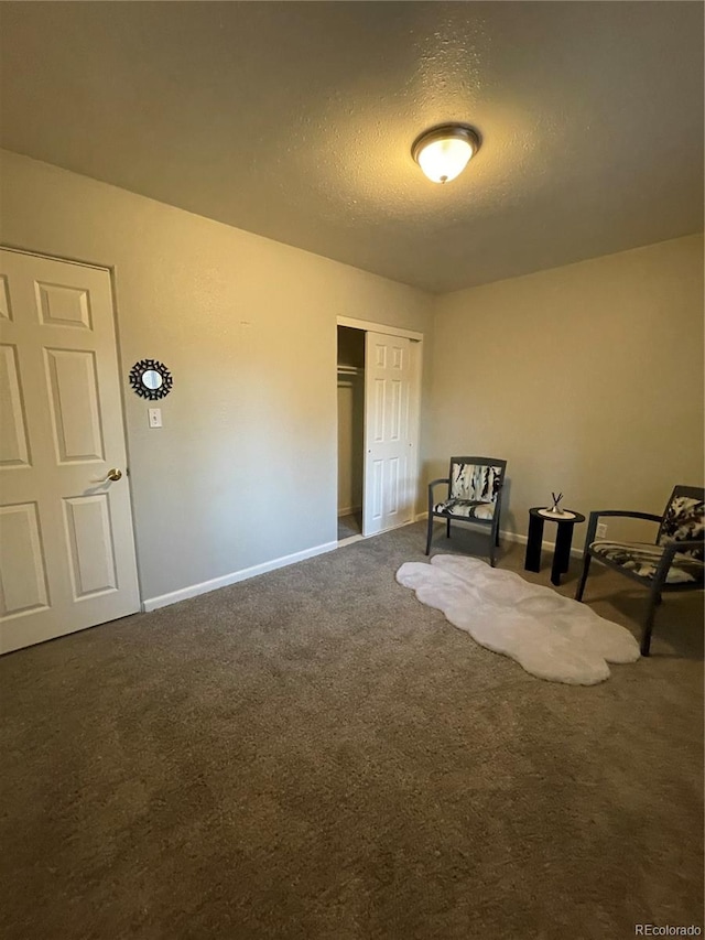 unfurnished room with a textured ceiling and dark colored carpet