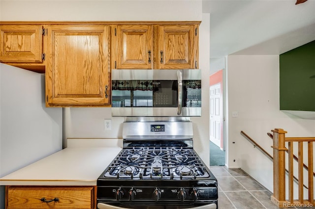 4511 S Braun Ct, Morrison, CO 80465 - kitchen featuring stainless steel microwave, black gas range oven, light countertops, freestanding refrigerator, and brown cabinetry