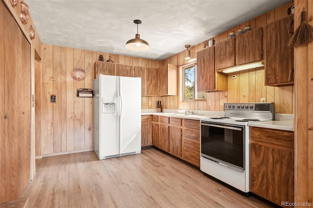 29 Deerfield Ln, Florissant, CO 80816 - kitchen with white appliances, light wood-type flooring, light countertops, brown cabinets, and wood walls