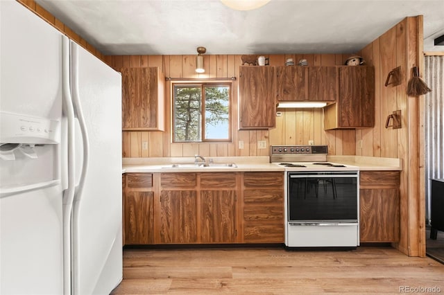 29 Deerfield Ln, Florissant, CO 80816 - kitchen featuring white appliances, a sink, brown cabinets, light countertops, and wood walls