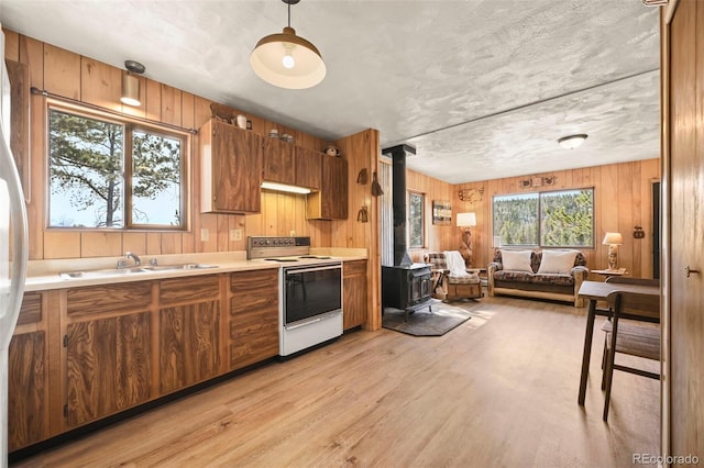 29 Deerfield Ln, Florissant, CO 80816 - kitchen featuring white electric stove, a wood stove, a sink, brown cabinetry, and light wood-style flooring
