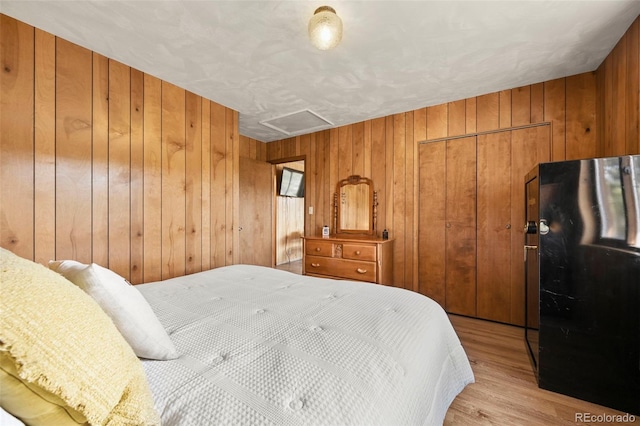 29 Deerfield Ln, Florissant, CO 80816 - bedroom featuring attic access, a closet, wood walls, light wood finished floors, and freestanding refrigerator