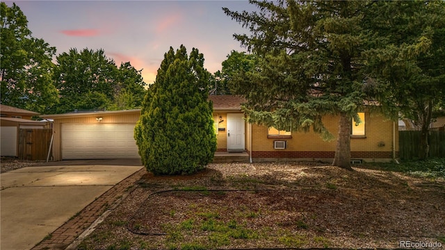 1235 S Benton St, Lakewood, CO 80232 - obstructed view of property featuring driveway, brick siding, and an attached garage