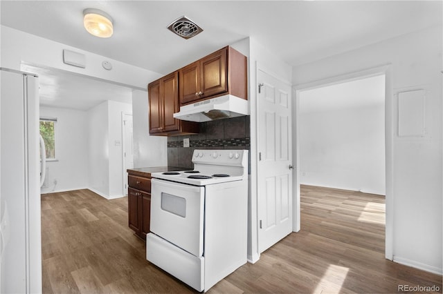 1235 S Benton St, Lakewood, CO 80232 - kitchen featuring white appliances, under cabinet range hood, wood finished floors, decorative backsplash, and brown cabinetry