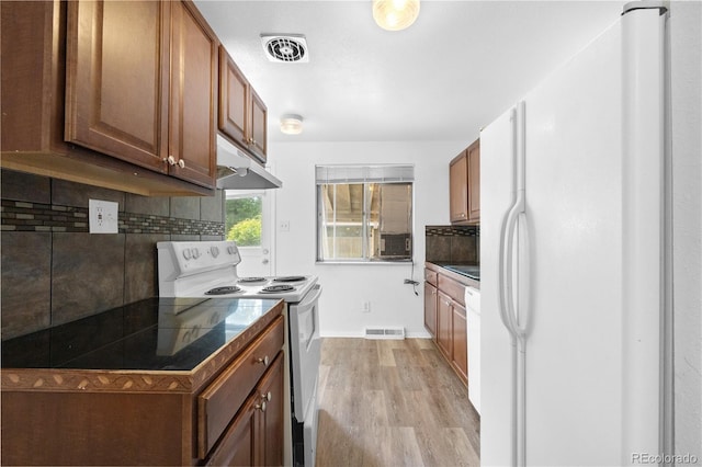 1235 S Benton St, Lakewood, CO 80232 - kitchen featuring white appliances, under cabinet range hood, tasteful backsplash, light wood-style floors, and brown cabinetry