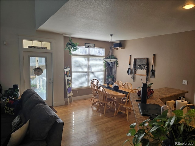 dining space with a textured ceiling and light hardwood / wood-style flooring