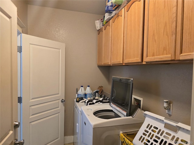 clothes washing area featuring cabinets and washer and dryer