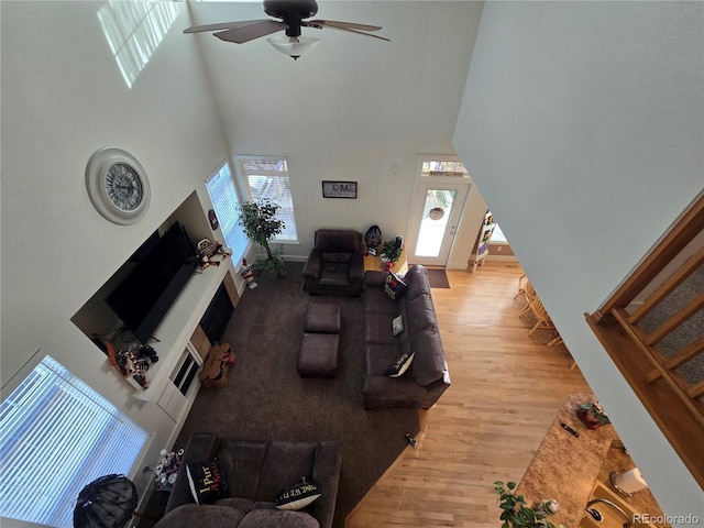 living room with a high ceiling, light wood-type flooring, and ceiling fan