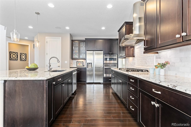 6728 S Catawba Way, Aurora, CO 80016 - kitchen featuring stainless steel appliances, wall chimney range hood, an island with sink, dark wood-style floors, and tasteful backsplash
