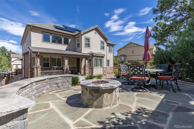6728 S Catawba Way, Aurora, CO 80016 - rear view of house with solar panels, an outdoor fire pit, outdoor dining space, stone siding, and a porch