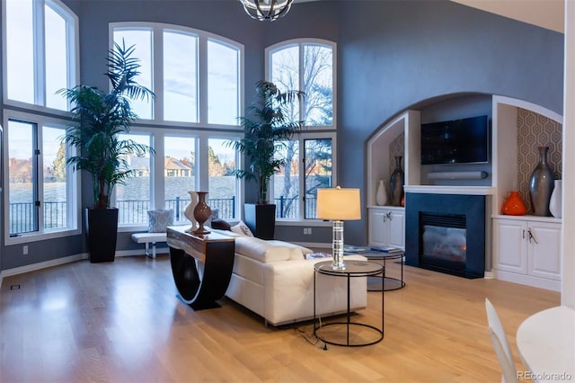 living room featuring a towering ceiling, wood-type flooring, and a wealth of natural light