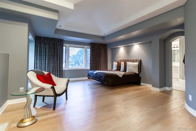 bedroom with a raised ceiling and light hardwood / wood-style flooring