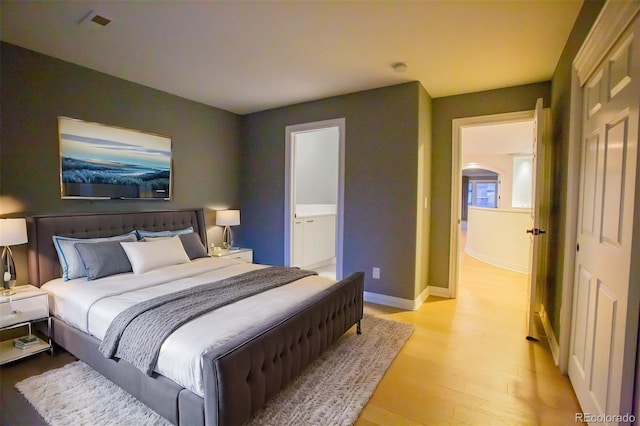 bedroom featuring ensuite bathroom and light hardwood / wood-style flooring