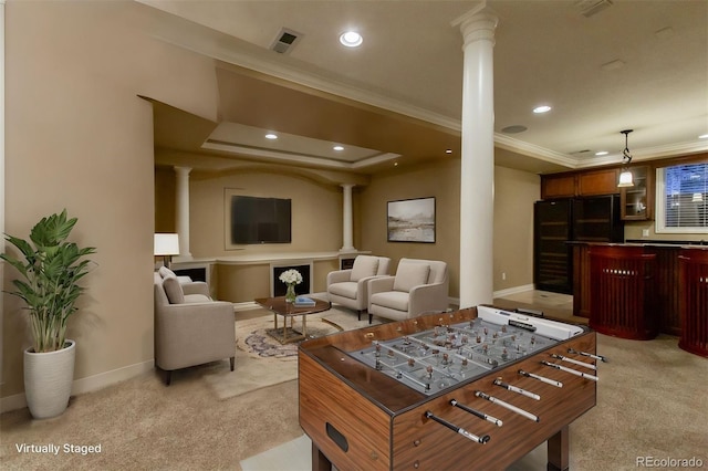 carpeted living room with a tray ceiling, ornamental molding, and decorative columns