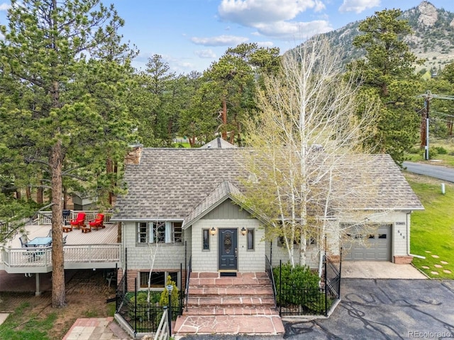 640 Pinewood Ln, Estes Park, CO 80517 - view of front of home featuring a shingled roof, an attached garage, asphalt driveway, a wooden deck, and a chimney