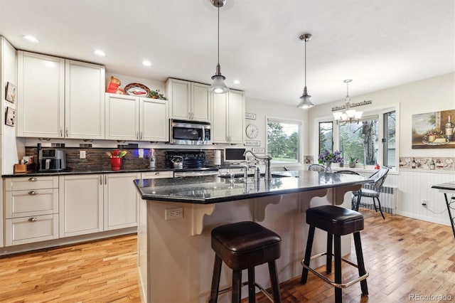 640 Pinewood Ln, Estes Park, CO 80517 - kitchen featuring stainless steel microwave, a sink, black range with electric stovetop, light wood finished floors, and wainscoting