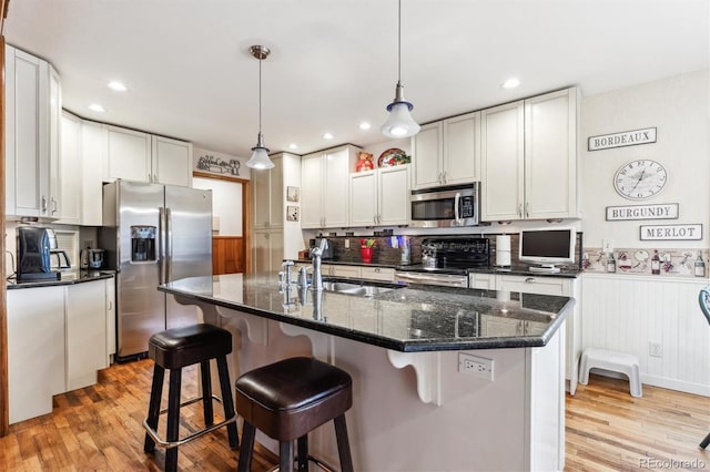 640 Pinewood Ln, Estes Park, CO 80517 - kitchen featuring stainless steel appliances, light wood finished floors, a wainscoted wall, a breakfast bar area, and a sink