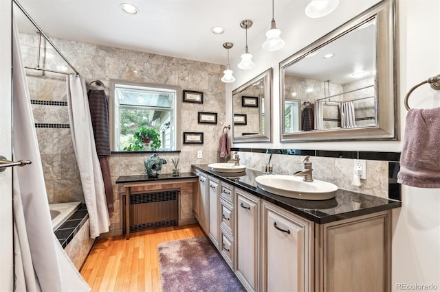 640 Pinewood Ln, Estes Park, CO 80517 - bathroom featuring radiator heating unit, double vanity, tiled shower / bath, wood finished floors, and backsplash