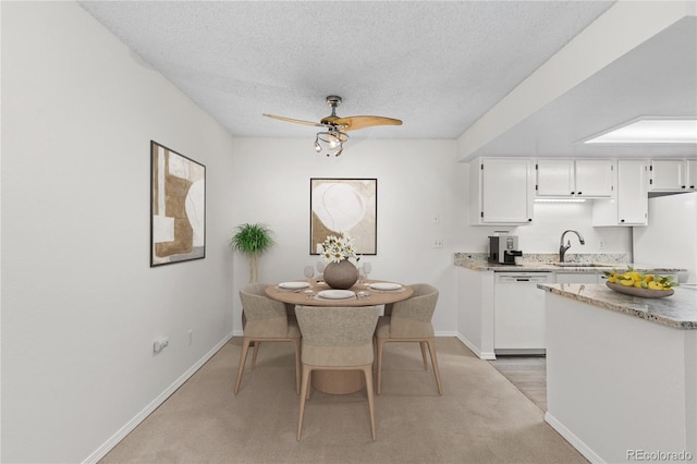 dining area featuring light carpet, sink, a textured ceiling, and ceiling fan