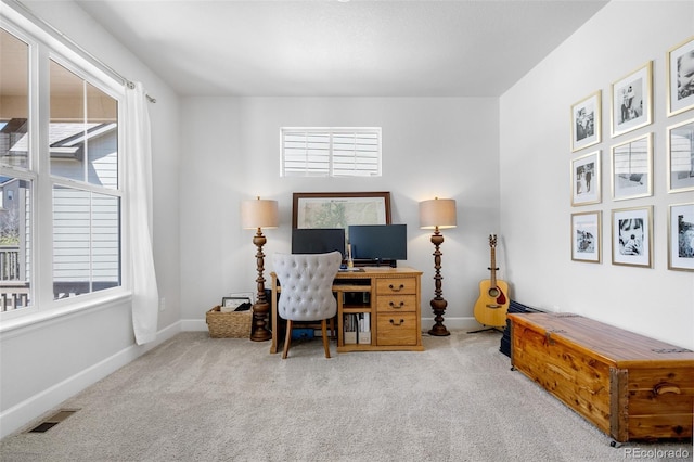 carpeted office featuring baseboards, visible vents, and a healthy amount of sunlight