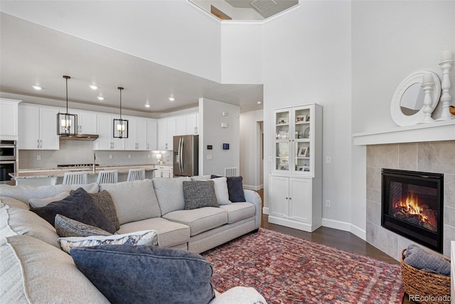 living room with a fireplace, baseboards, visible vents, and recessed lighting