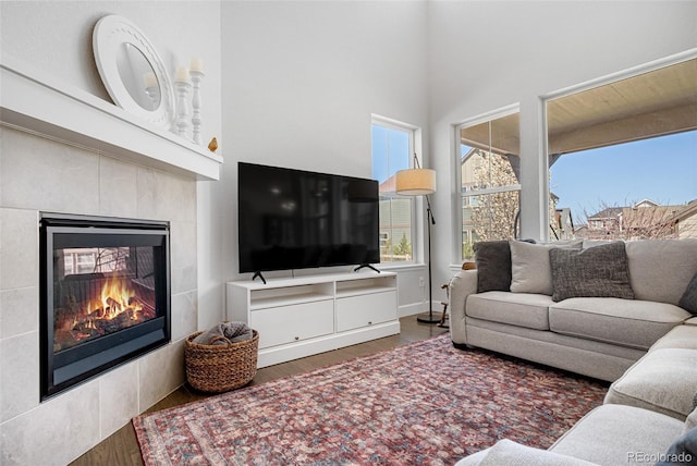 living area with a towering ceiling, wood finished floors, and a fireplace