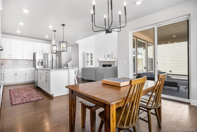dining space featuring plenty of natural light, an inviting chandelier, dark wood-style floors, and a tiled fireplace